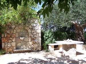 Stone built water feature, table and seating area under a shady tree