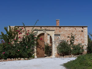 Stone bungalow with traditional wall and gate entrance into courtyard.