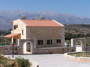 Stone bungalow with traditional wall and gate entrance into courtyard.